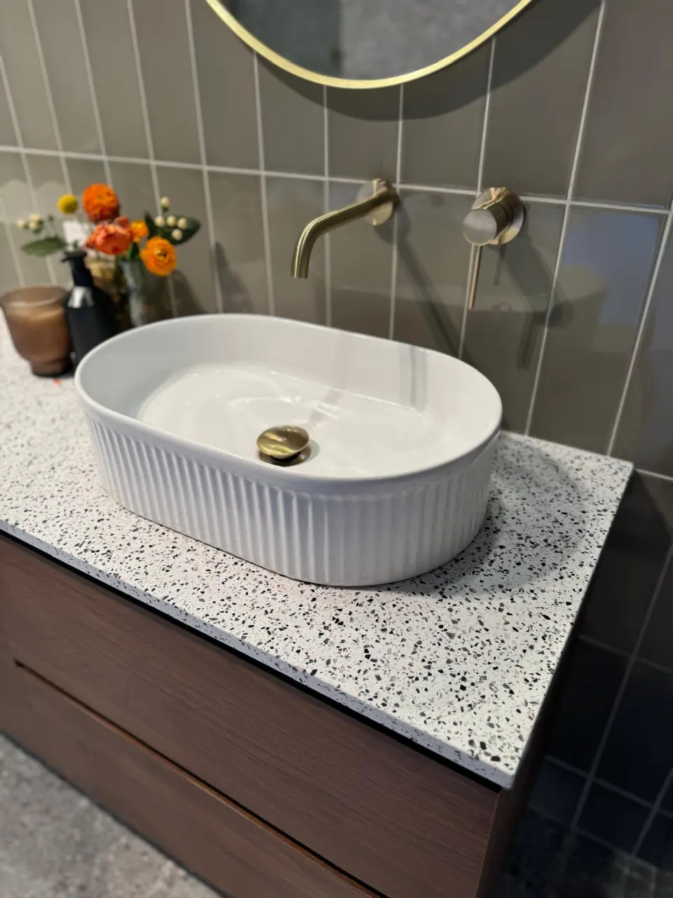Fluted vessel basin on a terrazzo-top vanity with a gold-finish wall tap