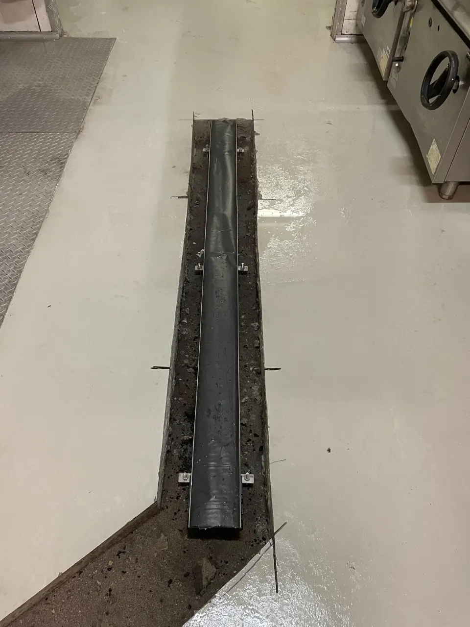 Channel drain laid in a cut-out in a commercial kitchen floor, ready for the floor to be made good