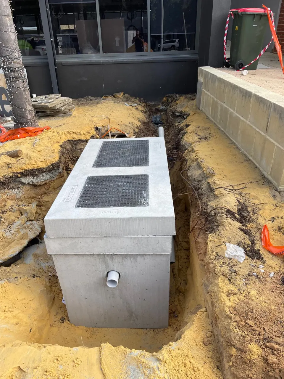 Precast concrete pit with two heavy-duty lids set in a sandy trench