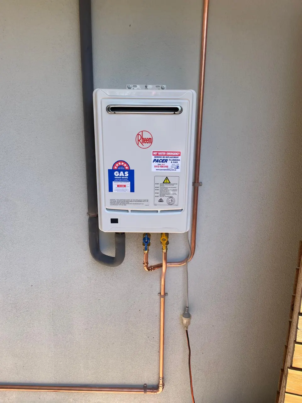 Rheem continuous flow gas hot water unit on an outside wall with copper gas and water pipework